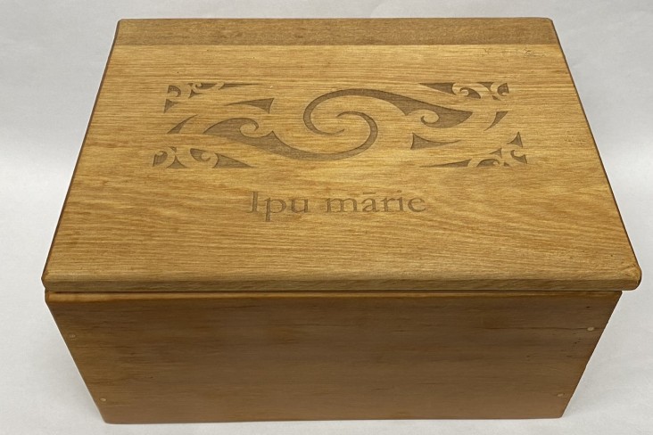 A wooden box with a carving on top.