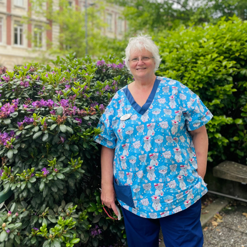 Linda in her Christmas-themed scrubs, in front of the old entrance to Dunedin Public Hospital - now Psychiatric Services Building.