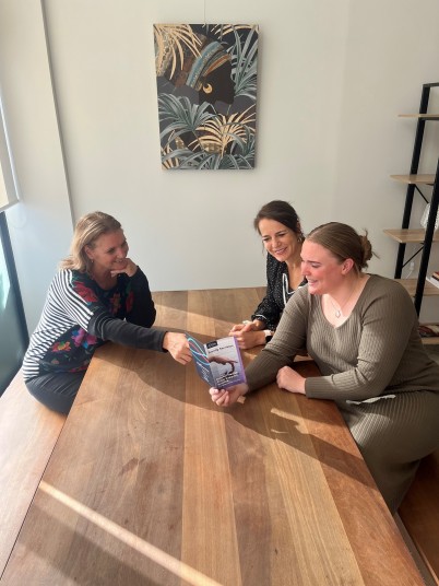 Three women sitting at a table looking at brochure 